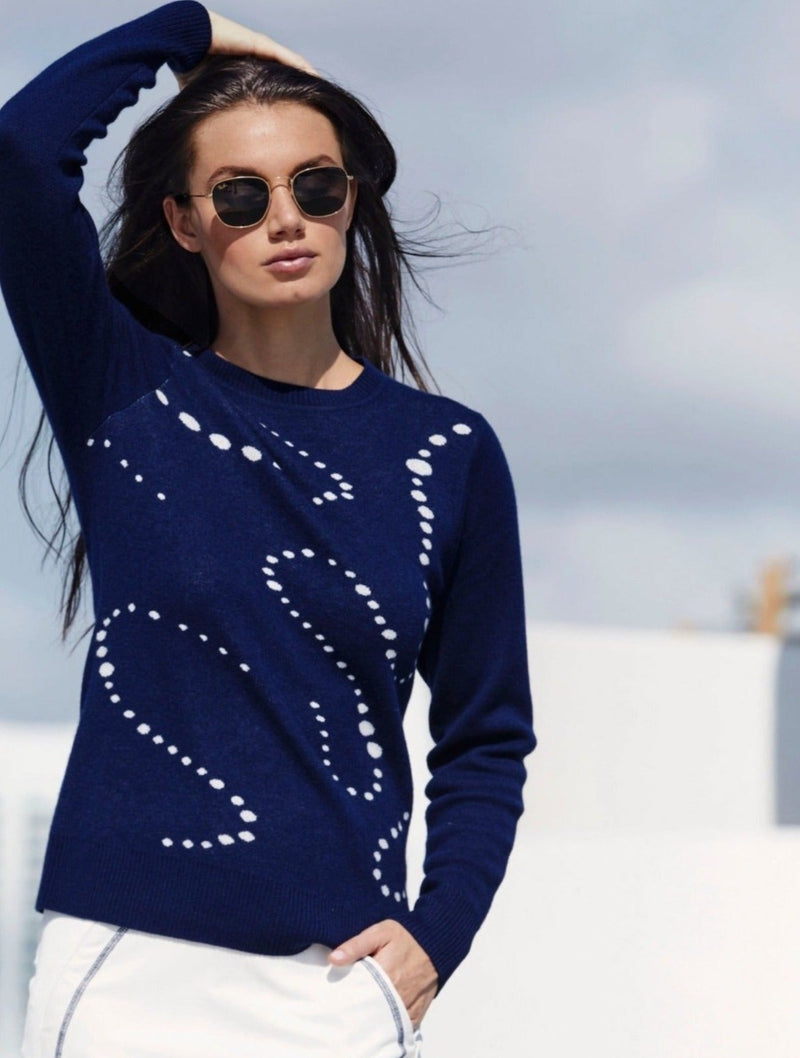 This image shows a woman wearing the Aubrey Merino-Viscose Crewneck, a luxurious and sustainable sweater made with a blend of merino wool, silk-like viscose -cellulose and cashmere. The sweater has a crew neckline The Aubrey sweater is exo-conscious and designed for active-casual luxury and all-day comfort.