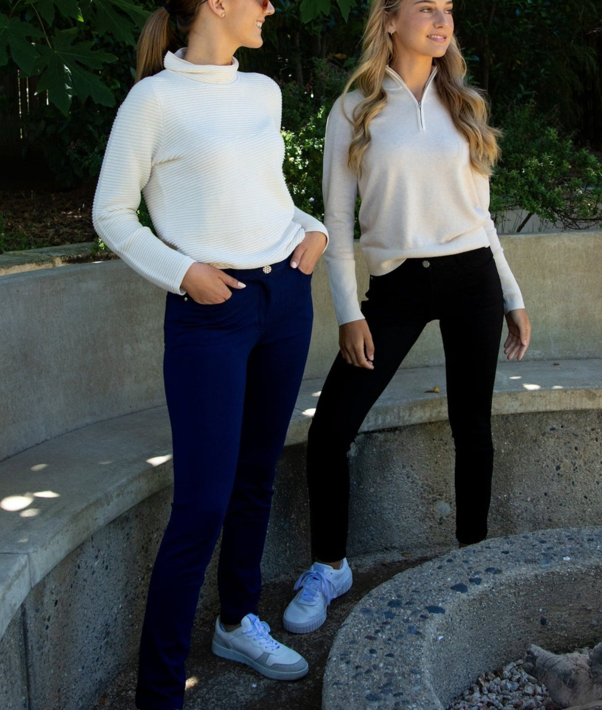This photo shows one woman wearing the Navy Eliza 5-Pocket Jersey pant with the Ellie Cotton Sweater, while the other woman wears the Eliza Pant in Black, paired with the Luna Organic Cotton 1/4-Zip Sweater in Linen Beige.