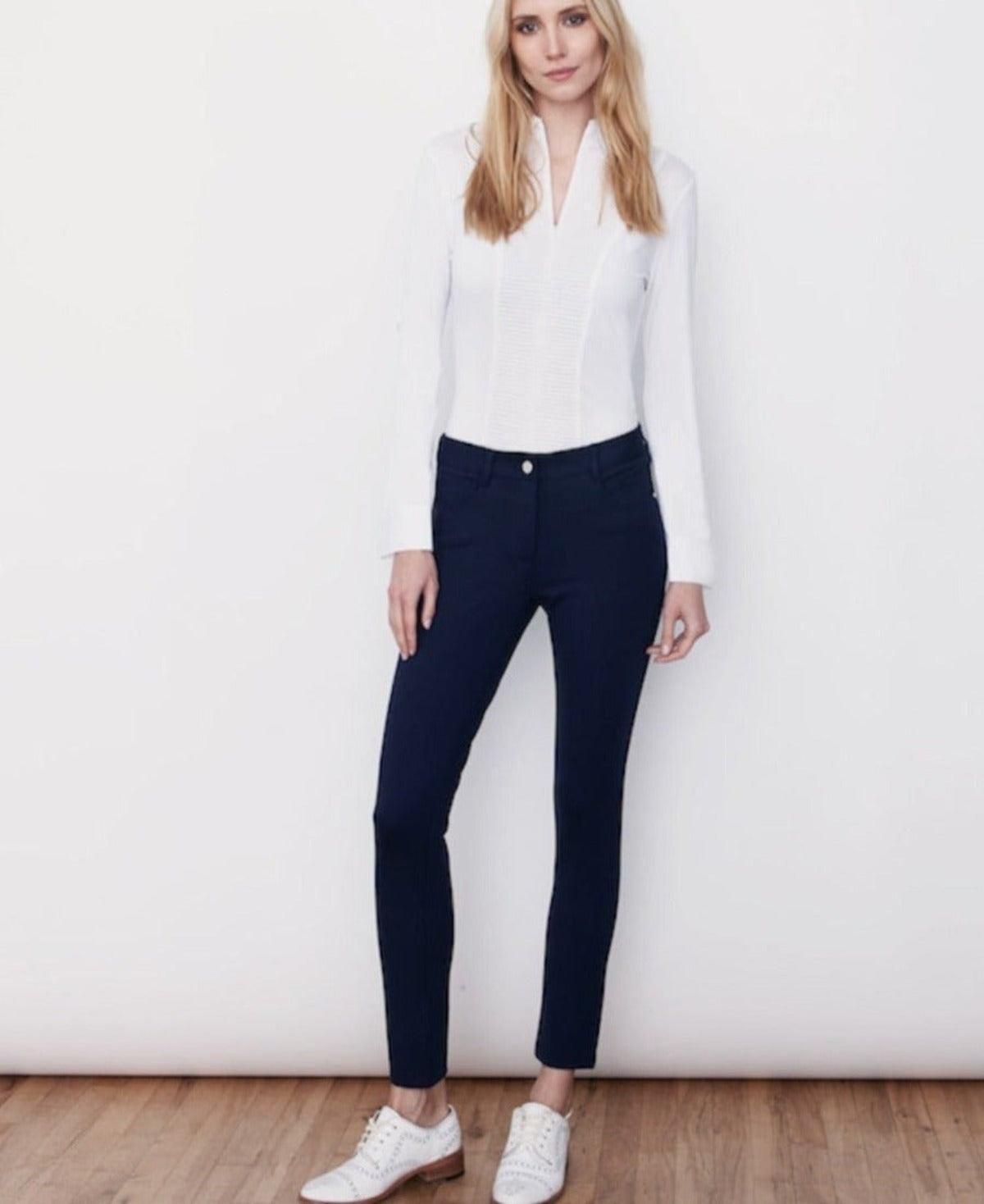 Sustainability Meets Luxury that Embraces Movement and Comfort. This image shows a woman wearing the Navy Stretch Jersey 5-Pocket Eliza Pant in Size 2, paired with a white Cindy 1/4 Zip Long Sleeve Top. This tailored fit pant has a 30" inseam and is available in US Sizes 0-14. 