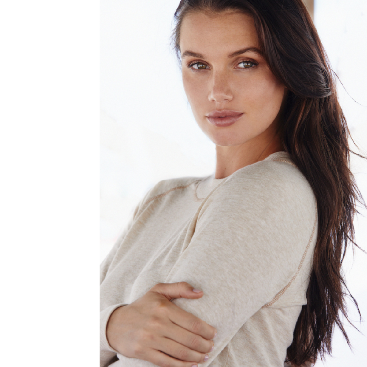 This photo shows a woman in a relaxed pose, embracing the delicate comfort and cozy softness  in the Restore Organic Cotton Crewneck. Minimalist neutrals, a vintage-inspired design combine to make this sweater your favorite go-to  style for quiet comfort after a long day.