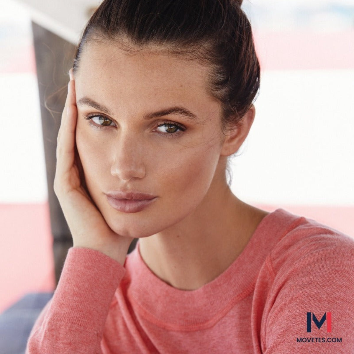 This image depicts a woman in an up-close image wearing the pastel red organic Restore Cotton Crewneck and her hair perfectly coiffed in a relaxed updo