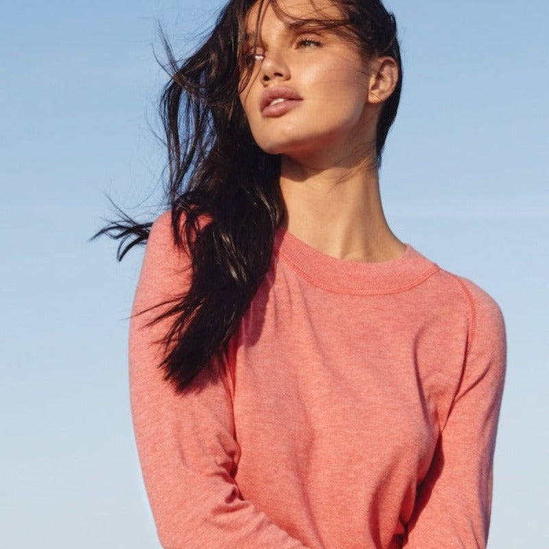 image of woman wearing a pastel red organic cotton crewneck with contrast tonal stitching.