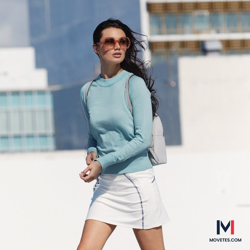 This image shows a woman's travel lifestyle while wearing the RESTORE Organic Cotton Crewneck in Vintage Boathouse Blue, Paired with the Powerstretch Jersey Impact Performance Travel Skort.