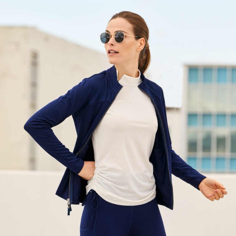 Image shows a woman sightseeing while wearing the Powerstretch Jersey Nova Jacket in Navy, paired with the Brooke top and Navy Leggings. Crafted in Premium Recycled Smooth Matte, Medium-Weight 4-way Stretch Jersey fabric, this jacket has a nice drape and weight for travel.