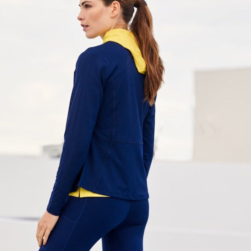 Image shows a woman wearing the Powerstretch Jacket in a side view. There's an early-morning fog in the background, creating a soft light. This comfortable, versatile Stretch Jersey Layering Jacket  is made using premium recycled materials and trims.UPF 50+. Classic Fit. 
