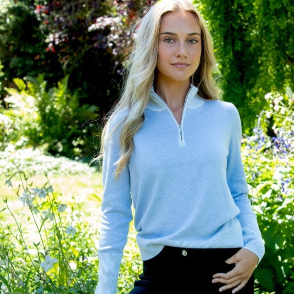 This image shows the versatile sporty style of the Luna 1/4 Zip Sweater, sustainably crafted of Organic Cotton and Seacell- Lyocell with plaited rib two-color 3" high cuffs, high neck collar and waistband. This image was photographed in a garden setting in natural sunlight
