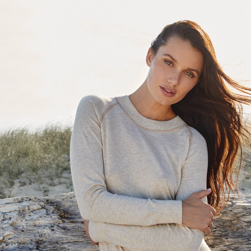 This image shows a woman wearing the RESTORE Organic Cotton Crewneck in Lynx, a soft neutral shade with contrast tonal topstitching. This vintage-inspired design is forever timeless and elegant.